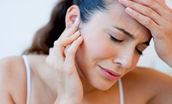 mujer con dolor de cabeza y oído por trastorno temporomandibular
